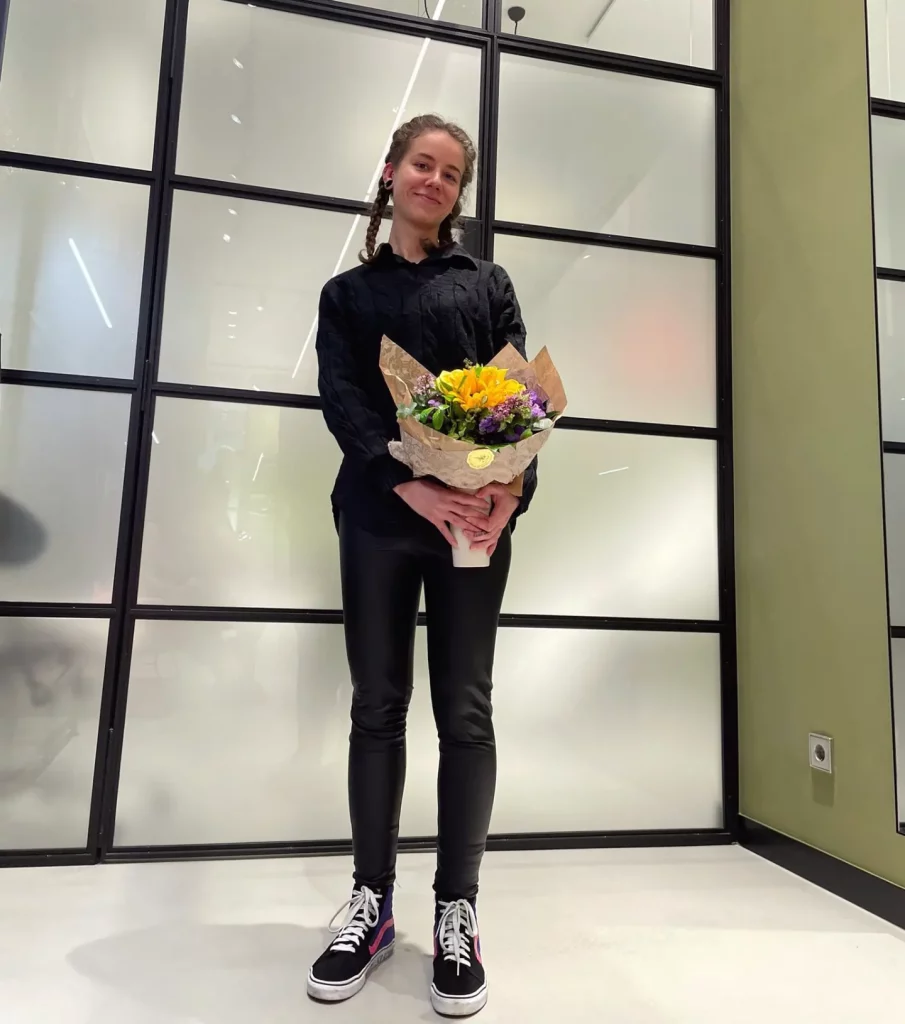 Lucy with a bouquet of flowers at the headquater of Saboteur Thomas Sabo in Vienna, smiling at the camera