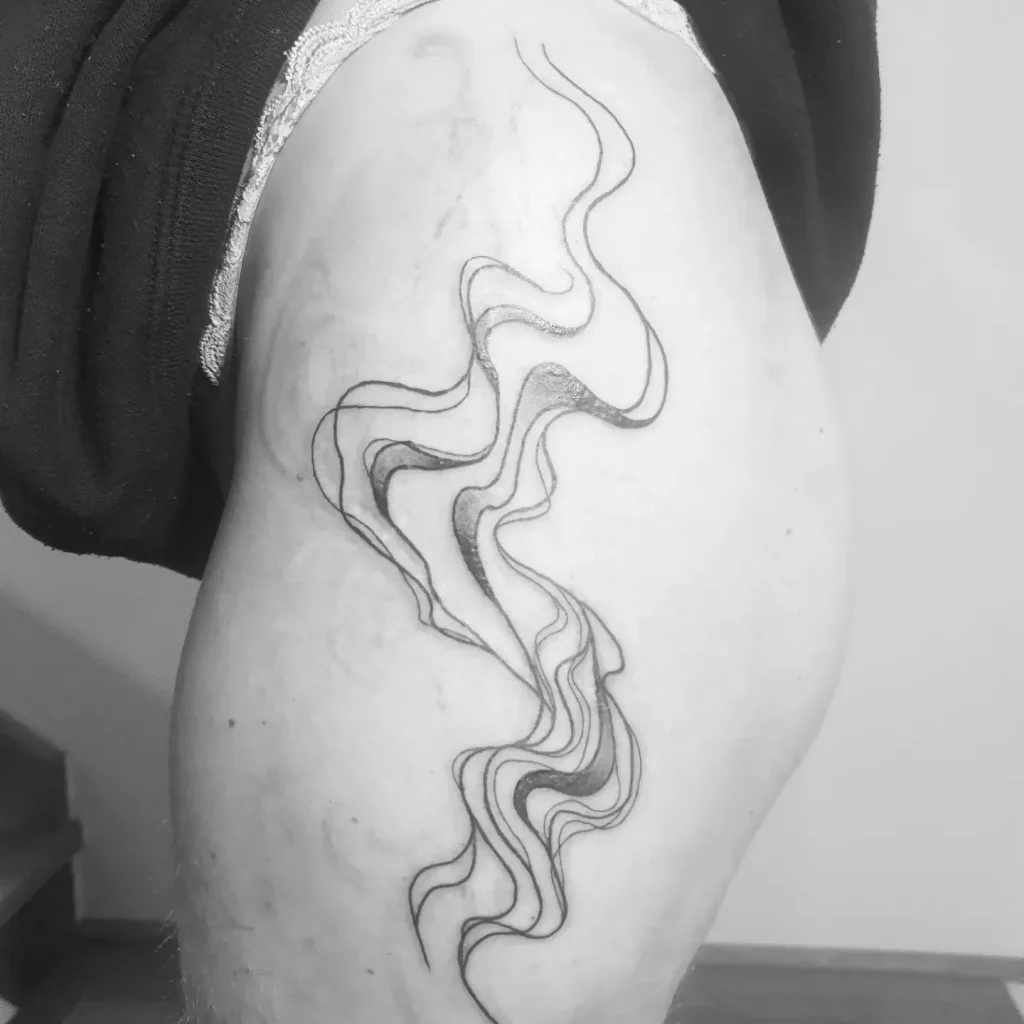 big black and grey tattoo that shows some freehand lines that look like waves or smoke, on hip.
